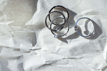 Silver rings on crumpled paper lit by the sun, jewelry background