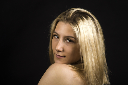 Studio portrait. Smiling girl with makeup and hairstyle on a dark background. Emotions when posing. Studio shot on dark background.Portrait of a smiling girl on a dark background.の写真素材