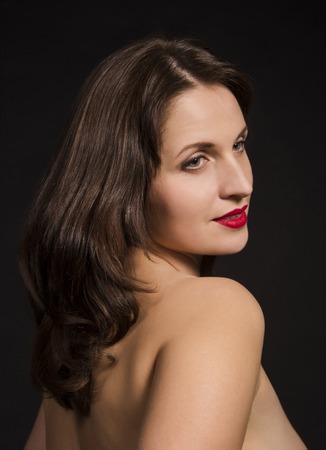 Portrait of naked woman with long hair and makeup on a dark background. Studio photography.の写真素材