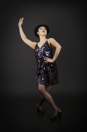 A young woman in a hat dancing.Studio shooting on a dark background.の写真素材