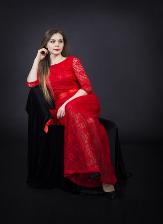 Portrait of beautiful smiling girl in a red dress.Studio shot on dark background, isolated image.の写真素材