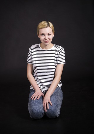 Young woman in striped t-shirt posing emotionally on dark background. Isolated image, Studio shot on dark background.の写真素材