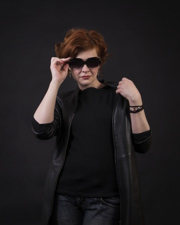 Emotional brunette posing in the Studio in a leather cloak.Isolated image on a dark background.の写真素材