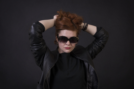 Emotional brunette posing in the Studio in a leather cloak.Isolated image on a dark background.の写真素材