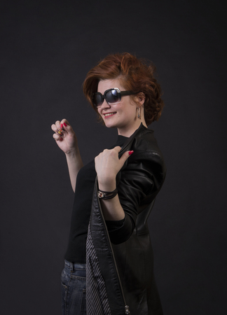 Emotional brunette posing in the Studio in a leather cloak.Isolated image on a dark background.の写真素材