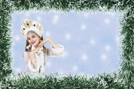 Christmas design-Christmas card with a beautiful, young, smiling woman dressed as Santa Claus, bordered by pine needles with a place for text. Studio photography.の写真素材