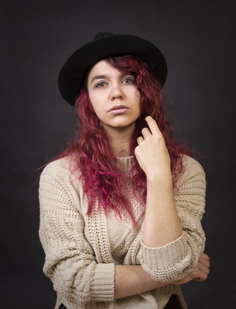 Emotional brunette in a hat and sweater with long hair posing in the Studio.Isolated images on a dark background.の写真素材