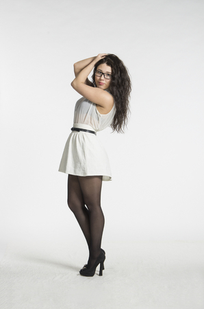 A girl with gorgeous long hair in a white blouse and white skirt emotionally posing. Studio shooting on a light backgroundの写真素材