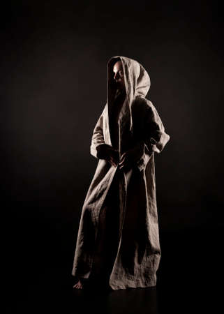 A young woman in a raincoat of coarse cloth on her naked body is isolated on a black background. Studio photography.の写真素材