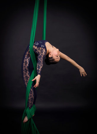 A young girl performs the acrobatic elements on the aerial silk.の写真素材