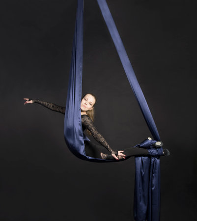 A girl performs the acrobatic elements on the aerial silk.の写真素材
