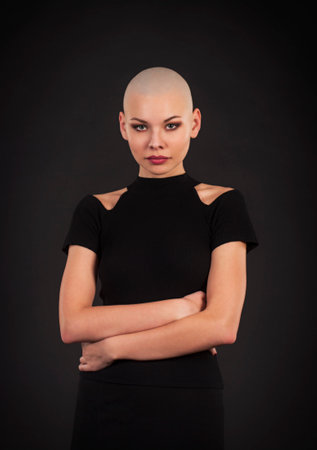 Emotional portrait of girl shaved bald.Studio shot on dark backgroundの写真素材