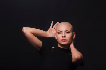 Emotional portrait of girl shaved bald.Studio shot on dark background..の写真素材