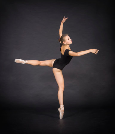 Young ballerina in a black leotard on a black backgroundの写真素材