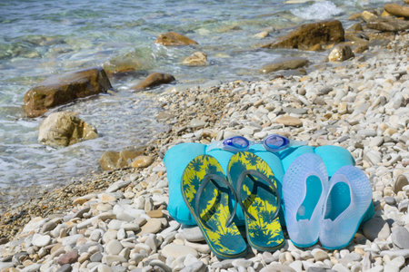 flip flops and glasses by the sea on a background pebbles of stones