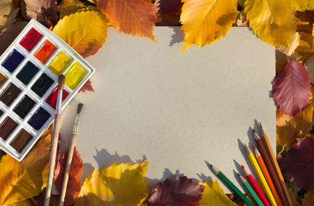 a sheet of white paper, paints, brushes, pencils and autumn leaves, autumn backgroundの写真素材