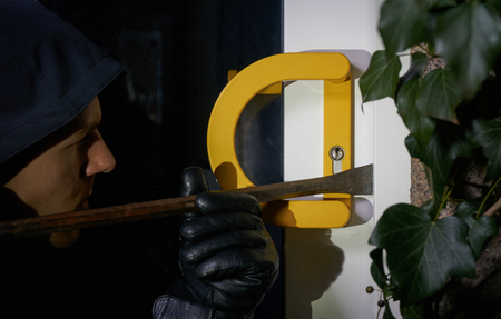 burglar trying to get into a house using a crowbar with torchlight flareの写真素材