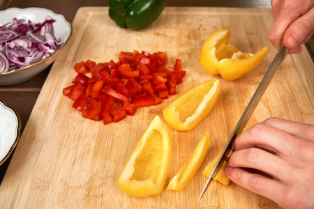 Cook chops ingredients for a meal on a cutting board in the kitchen.の写真素材