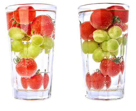 Cherry tomatos and grapes in a glas with water and air bubbles.の写真素材
