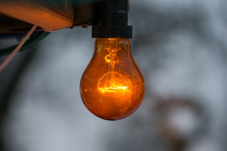 Old orange light bulb with a grey winter backgroundの写真素材