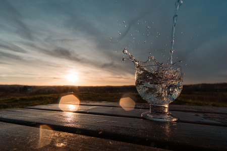 Water splash in the sunset frozen in motion. Teal and orange look against the sunlight with lensflares.の写真素材
