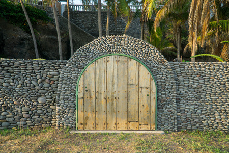 Wooden door and stone wall at the beach at sunset.の写真素材