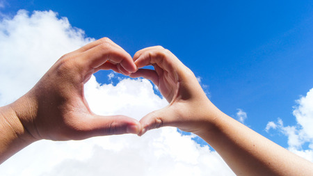 A couple made a heart shape from each other hand in the skyの写真素材