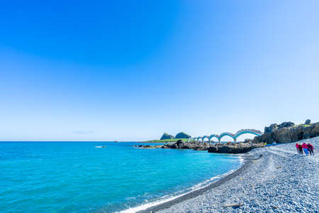 Beautiful scenic of Sanxiantai arch bridge with blue ocean with Three saint island in behind at Chenggong district in Taitung city, Taiwan.の写真素材