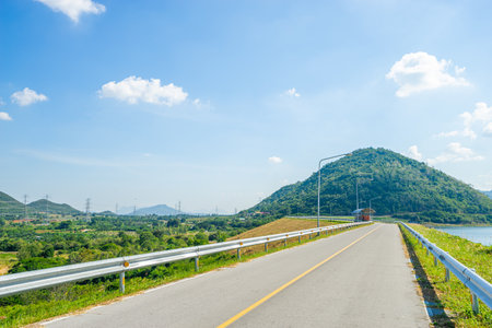 Beautiful scenic of the road in dam ridge with green grass at water dam (Pranburi Dam) in Prachuap Khiri Khan, Thailand.の写真素材