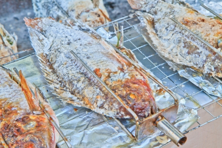 fishes roasting in a  steel rod over fireの写真素材