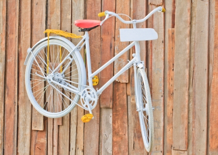 classic white bicycle hanging on old wooden wall and white plate の写真素材