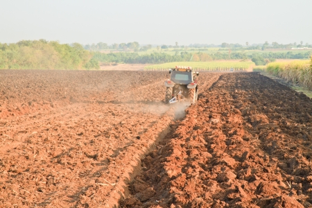 Small scale farming with tractor and plow in fieldの写真素材
