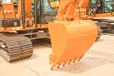 The scoop of a backhoe on  a concrete floor