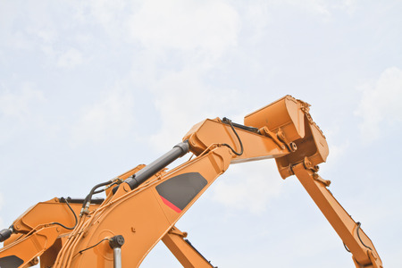 The scoop of a backhoe on a cloudy sky background