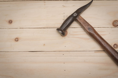 Hammer and metal nails on a woodgrain background
