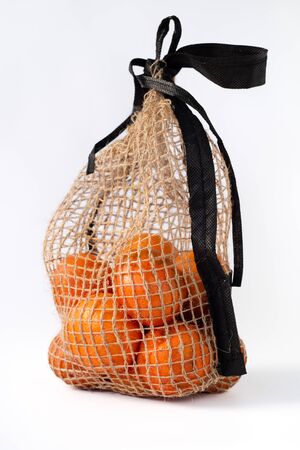 Citrus fruits in a grid of natural materials on a white  background. Eco-packaging. Bright orange tangerines. Natural light.の写真素材
