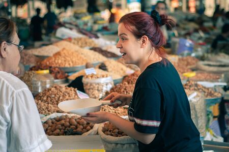 Bodrum, Turkey - August 23, 2019. Beautiful Turkish woman sells nuts and dried fruits in the marketのeditorial素材