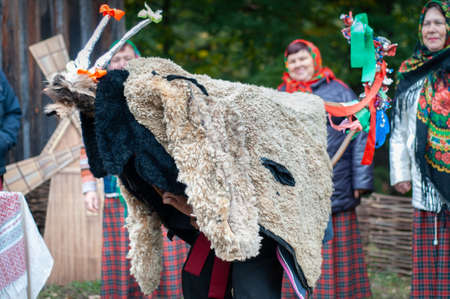 Belarus, urban village Glusha - October 5, 2019. A man in a goat-like costume participates in the Carol celebration. Traditional autumn harvest festival. People and traditions.のeditorial素材