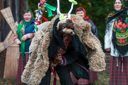 Belarus, urban village Glusha - October 5, 2019. A man in a goat-like costume participates in the Carol celebration. Traditional autumn harvest festival. People and traditions.のeditorial素材