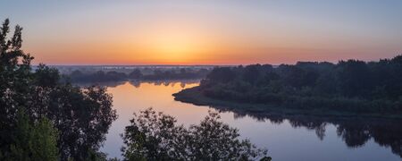 Summer landscape in Belarus. Colorful sunrise over a beautiful river and foggy fields.の写真素材