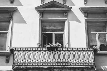 Lviv, Ukraine - July 19, 2019. A man with glasses on the balcony of a beautiful old building of the market square of the city of Lviv. Black and white.のeditorial素材