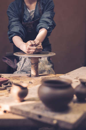 In the ceramics workshop. A young girl is learning pottery. Place for your text. Retro style with grain for film photography.の写真素材