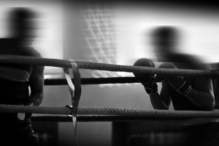 Black and white silhouettes of boxing athletes in the ring. Combat sports. Shallow depth of field,...