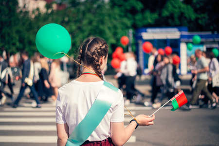 The last call at school. A teenage girl in school uniform with a green balloon in her hand. Parade of schoolchildren, graduates with bright balloons colorful in hands.の写真素材