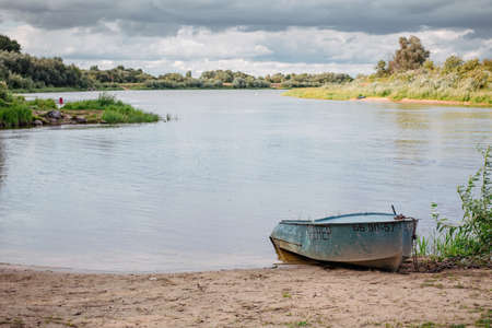 Beautiful smooth surface of the river with a boat on the sandy shore.の写真素材