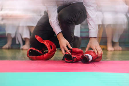 The Referee checks the protective helmet and gloves. Combat sports background in vintage style with film noise effect and motion blur. Focus on helmets and gloves.の写真素材