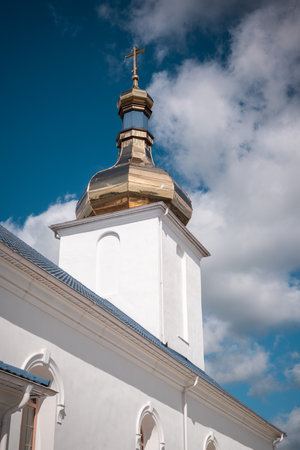 The golden dome of the church with the cross of the Blessed Virgin Mary against the blue sky in the Belarusian village.の写真素材