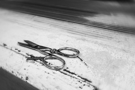 Beautiful scissors for cutting leather on a production metal table. Grainy film style with circular motion blur effect.の写真素材