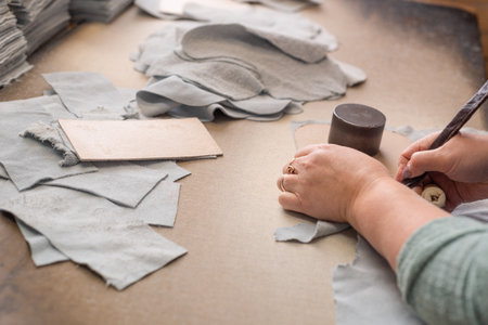 Women's hands are cutting leather at the table in the workshop.の写真素材