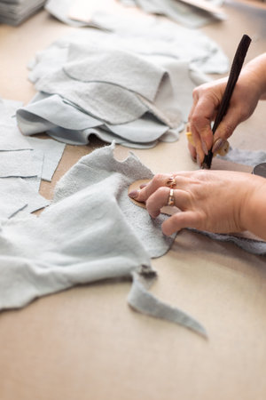 Women's hands are cutting leather at the table in the workshop.の写真素材